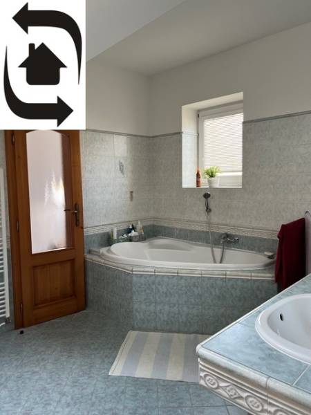 A bathroom in a 5 or more room apartment with a corner bathtub and wooden doors.