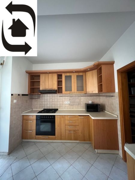 A kitchen in a 5 or more room apartment with wooden cabinets and appliances, tiled floor.