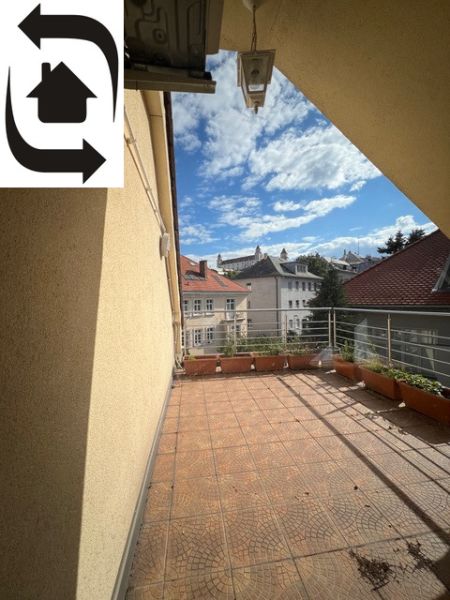 A balcony in a 5 or more room apartment with a view of the rooftops and blue sky.