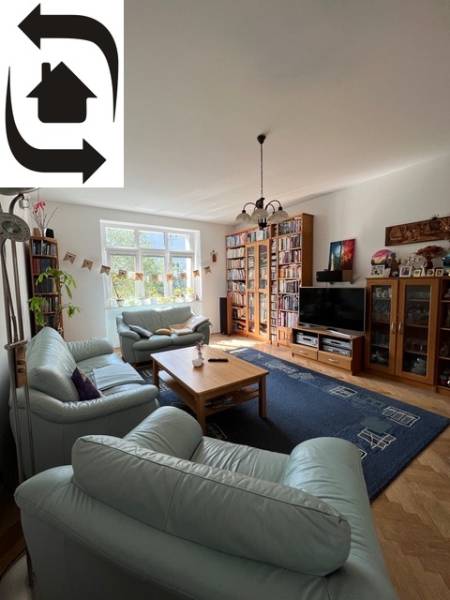 Living room of a five or more room apartment with a leather sofa, TV, and bookshelves.
