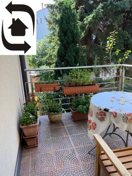 A balcony of a 5 or more room apartment with flower boxes and a wooden bench.