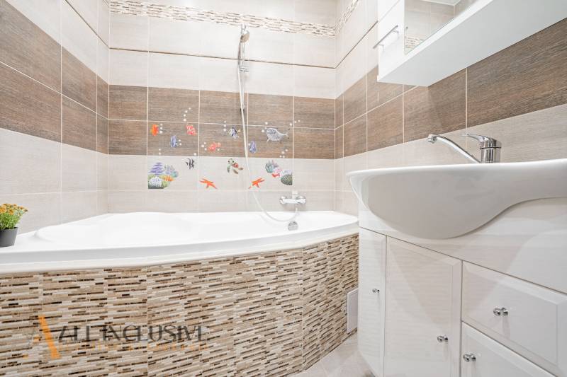 A bathroom in a 3-room apartment with a bathtub, a sink, and mosaic sea motifs.