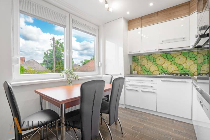 A kitchen with a table and chairs in a 3-room apartment, bright decor, and a large window.