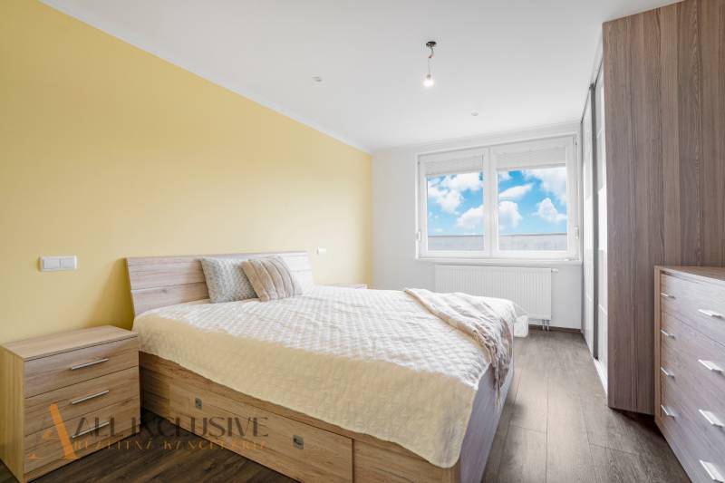 A bright bedroom in a 3-room apartment with wooden furniture and a large window.