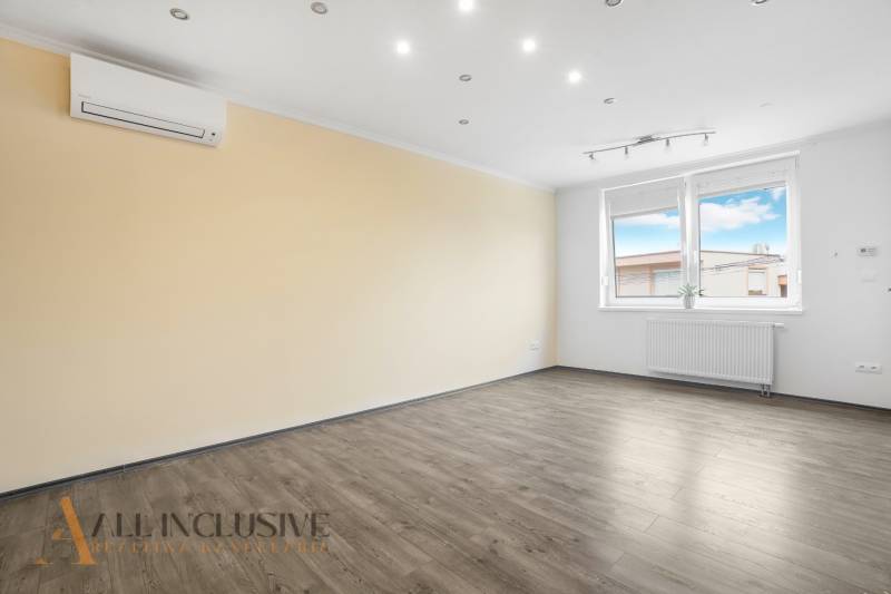 A bright room with laminate flooring, air conditioning, a window, and a radiator in a 3-room apartment.