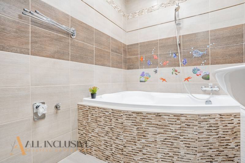 A bathroom in a 3-room apartment with a bathtub, decoration, and tiles in a colorful design.