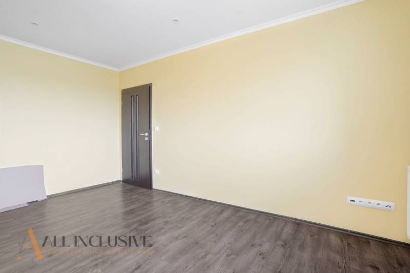 A spacious room with wooden flooring and yellow walls in a 3-room apartment.