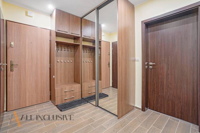 An entrance hall with wooden furniture and a mirrored wardrobe in a 3-room apartment.