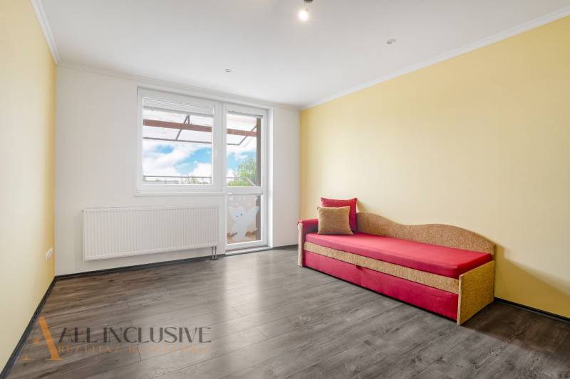 Bright living space in a 3-room apartment with wooden flooring and a sofa.