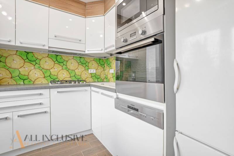 Modern kitchen in a 3-room apartment with colorful mosaic and built-in appliances.