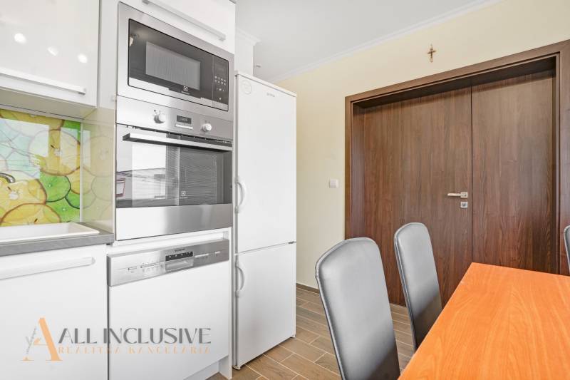 A kitchen in a 3-room apartment with modern appliances and a wooden dining table.