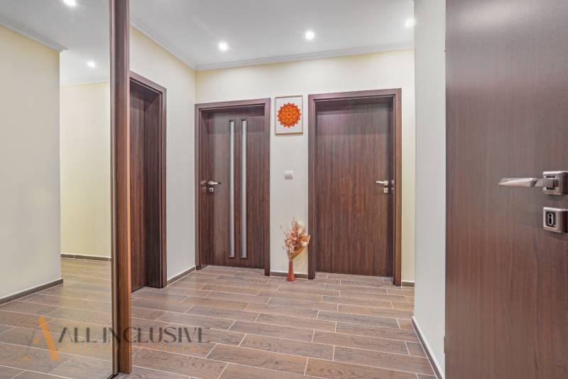 Interior of a 3-room apartment with wooden doors and flooring, subtle wall decoration.