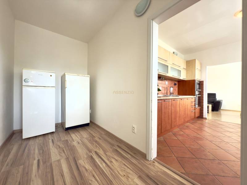 A kitchen in a 3-room apartment with a wooden floor and white appliances.