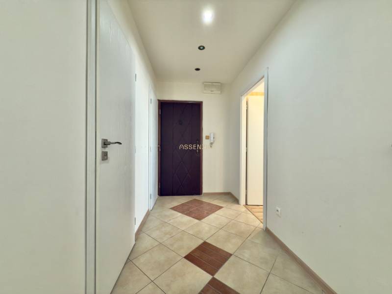 A hallway in a 3-room apartment with light walls and tiled flooring.
