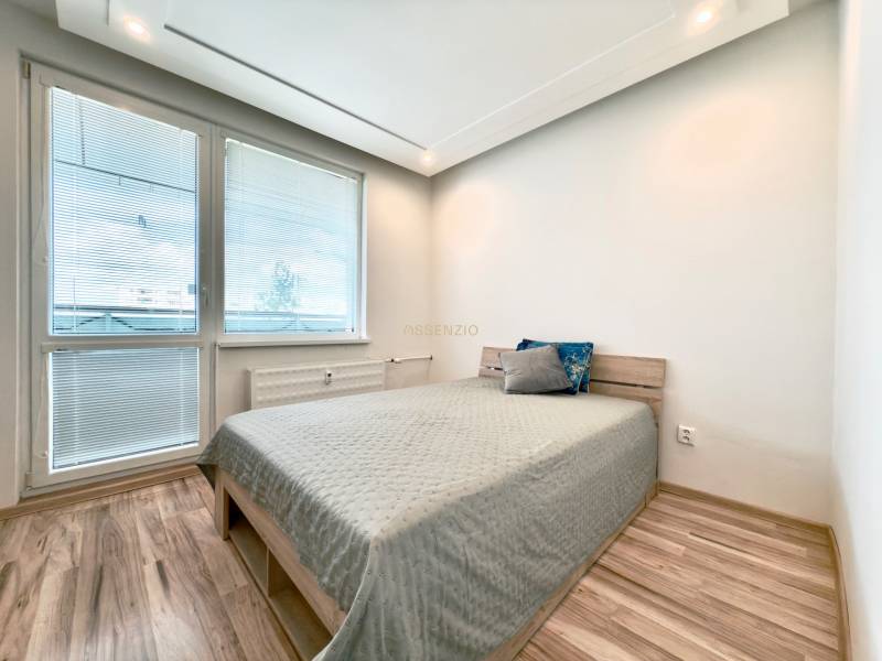 Bright bedroom in a 3-room apartment with a bed and wooden flooring.