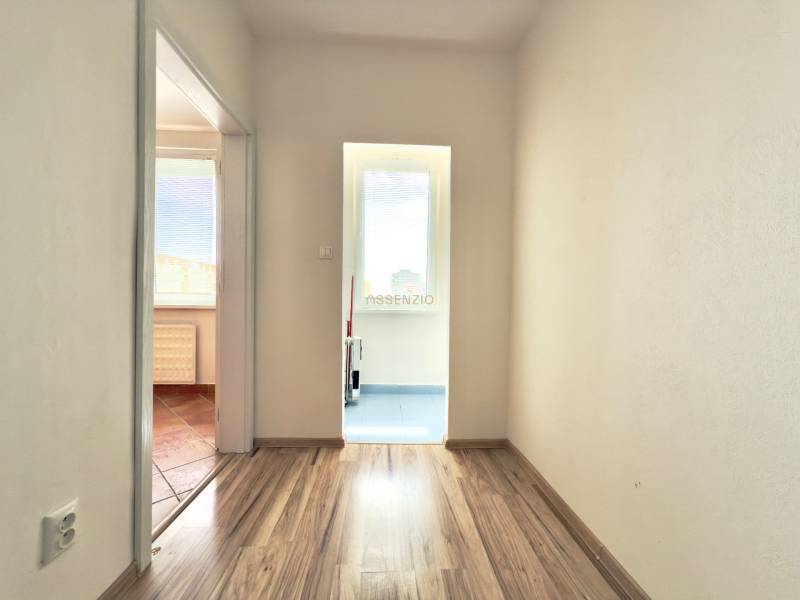 A hallway in a 3-room apartment with a wooden floor and a view of two rooms.