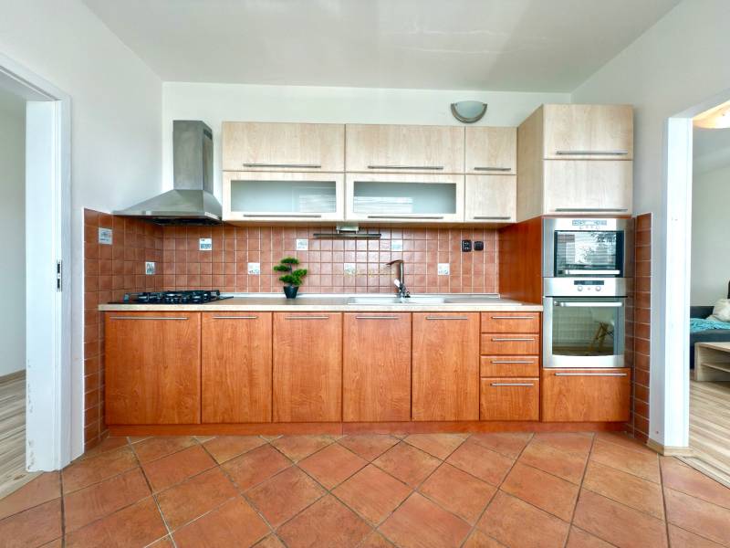 A kitchen in a 3-room apartment with wooden cabinets and ceramic tiles.