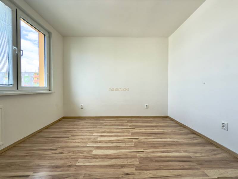 A room with laminate flooring and a window in a 3-bedroom apartment.