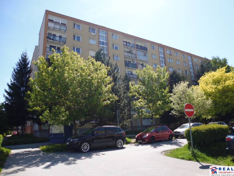 Apartment building on Karpatská Street in Prešov, surrounded by trees and parked cars.