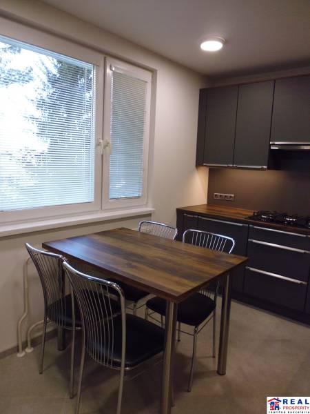 A kitchen in a 3-room apartment with a wooden table and four metal chairs.