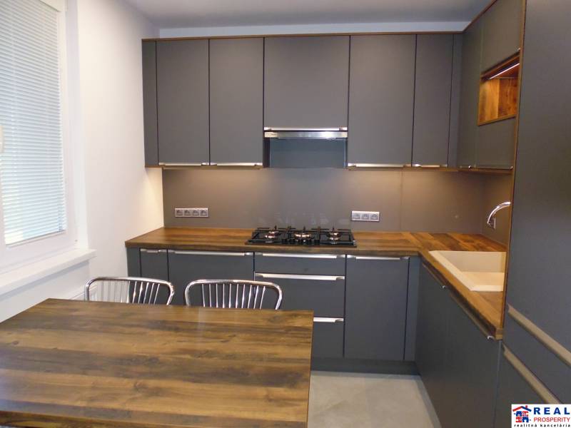 A kitchen with dark cabinets and a wooden countertop in a 3-room apartment.