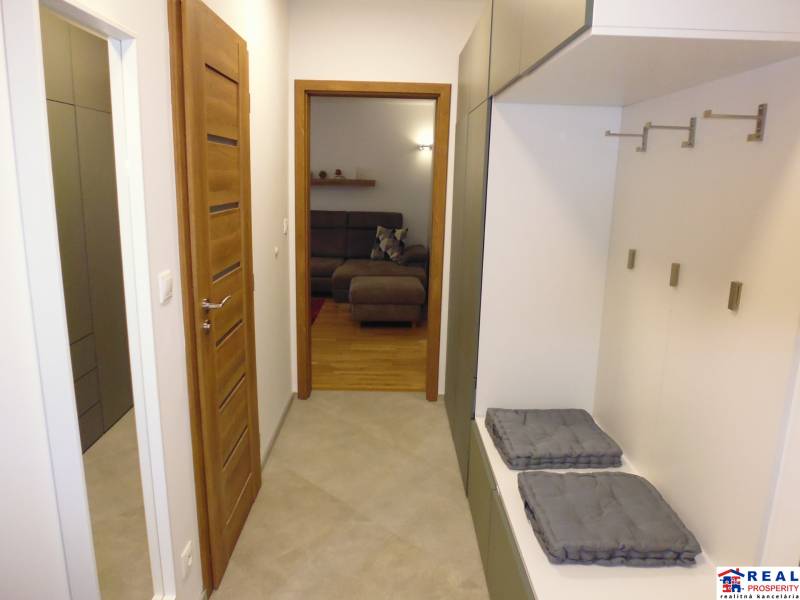 A hallway with a wardrobe wall leads to the living room in a 3-room apartment.