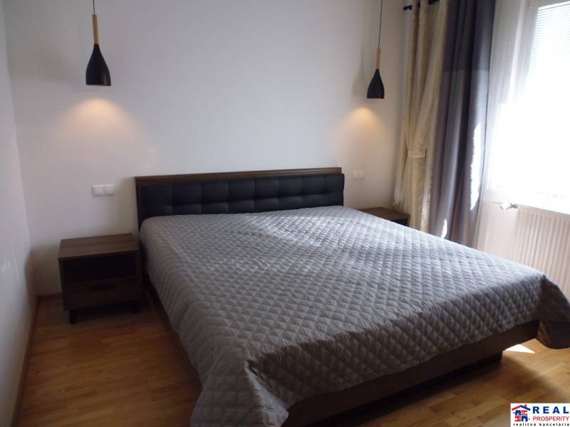 A bedroom with a large bed and two nightstands in a three-room apartment.