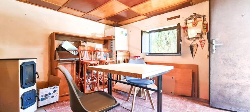 The interior of a cottage with furniture, a table, chairs, and an open window.