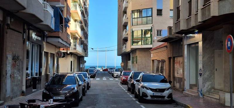 A street in the city of Torrevieja with a view of the sea, surrounded by apartment buildings.