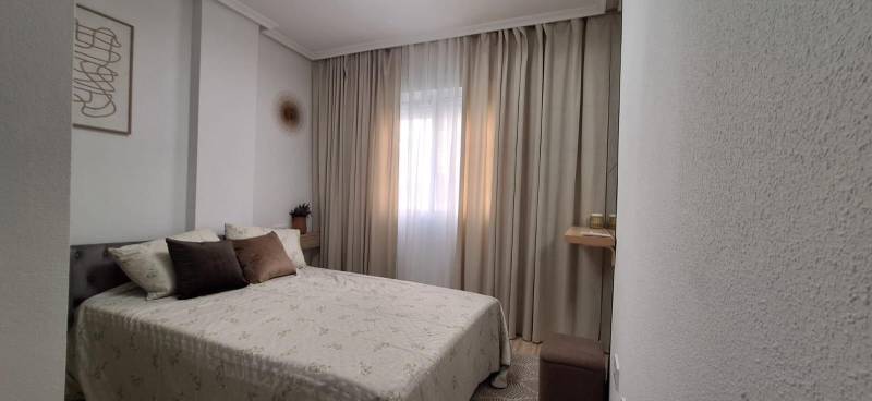 Bedroom in a 3-room apartment with a bed, curtains, and decorative pillows.