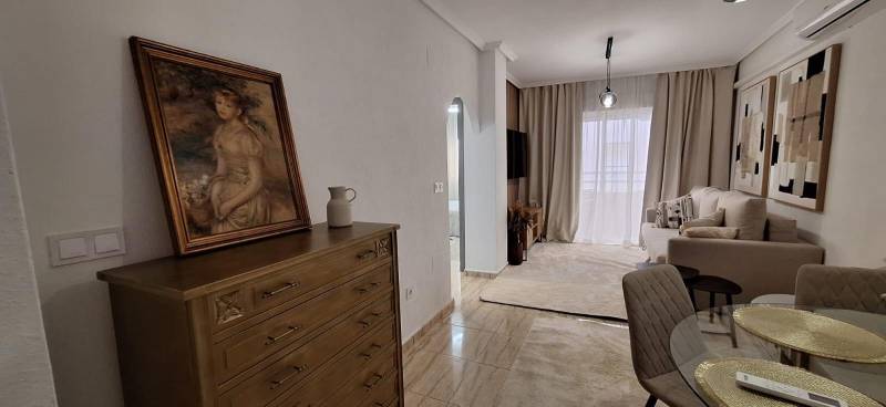 Living room in a 3-room apartment with paintings, furniture, and curtains.