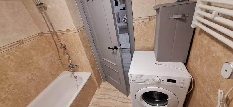 Bathroom with a bathtub, washing machine, and doors in a 3-room apartment.