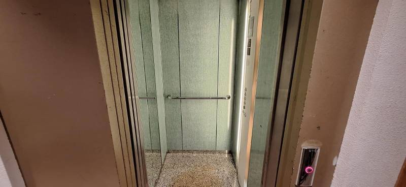 Open elevator with handrails and control panel.