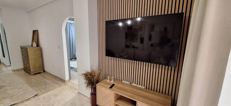 A stylish interior of a 3-room apartment with a TV on a wooden wall.