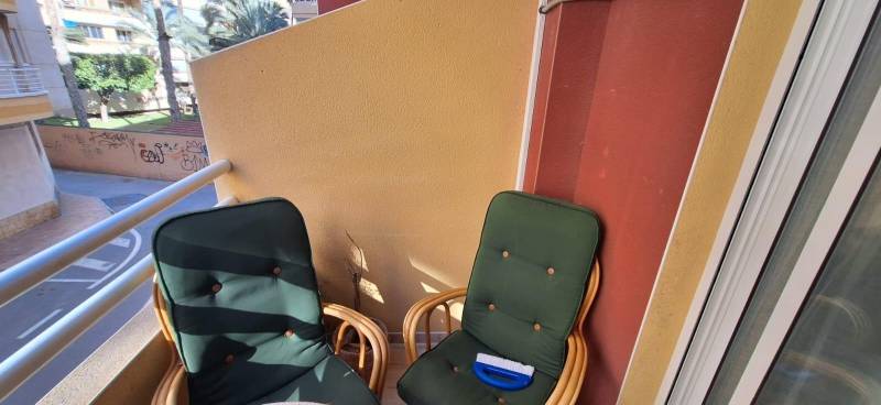 The balcony of a 3-bedroom apartment in Torrevieja with two armchairs and a chair.