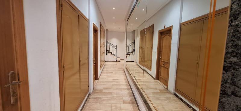 A long hallway with wooden doors and a mirrored wall in a 3-room apartment.