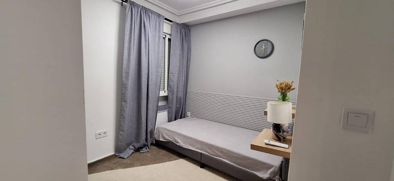 Bedroom in a 3-room apartment with a bed, clock, and nightstand.