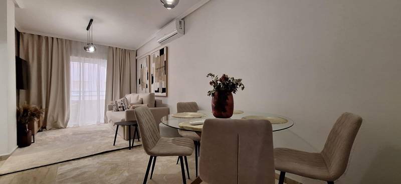 An elegant interior of a 3-room apartment with a table and sofa, in subtle shades.