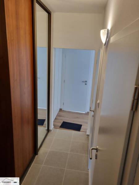 Entrance hallway in a 2-room apartment with tiles, a wardrobe, and white doors.