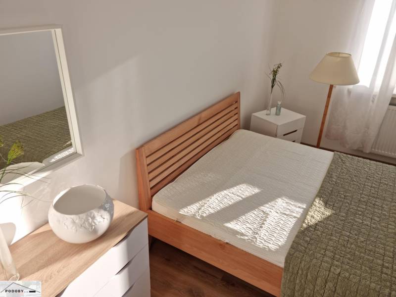A bright bedroom with a wooden bed and a lamp in a two-room apartment.