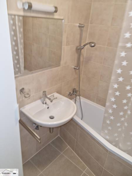 Bathroom with a bathtub, sink, and mirror in a 2-room apartment.
