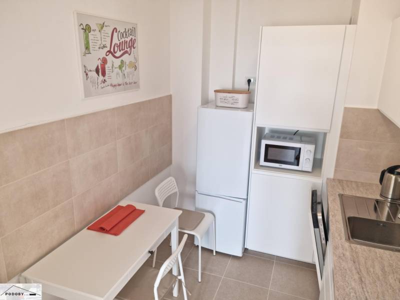 Dining room in a 2-room apartment with white furniture and kitchen appliances.