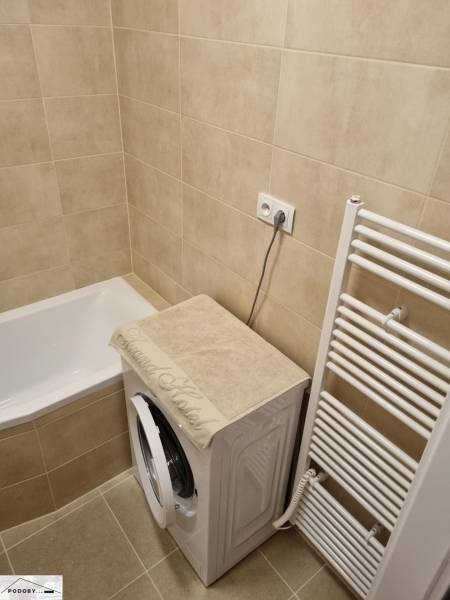 Bathroom with a bathtub, washing machine, and ladder radiator in a 2-room apartment.
