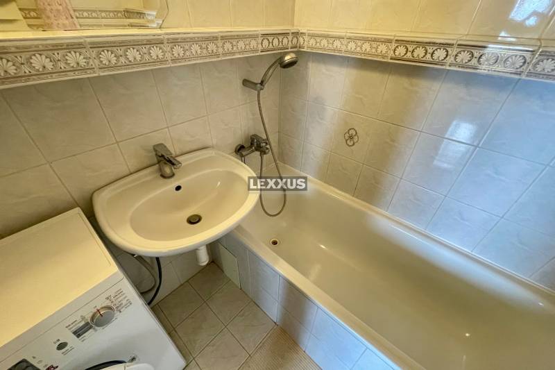 Bathroom with a sink, bathtub, and washing machine in a 3-room apartment.