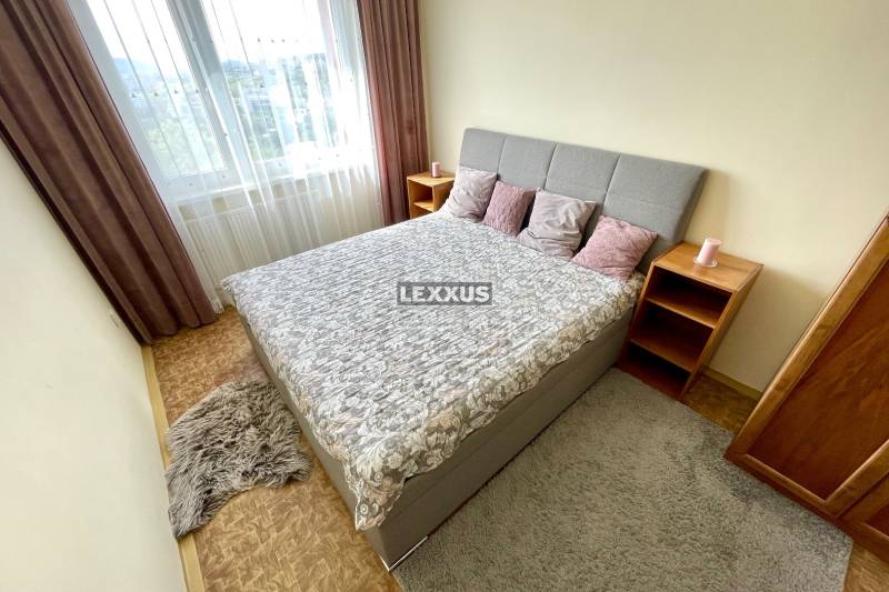 Bedroom with a bed, pillows, and nightstands in a three-room apartment.
