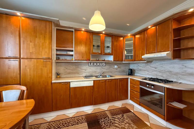 A kitchen in a 3-room apartment with wooden cabinets and a marble countertop.