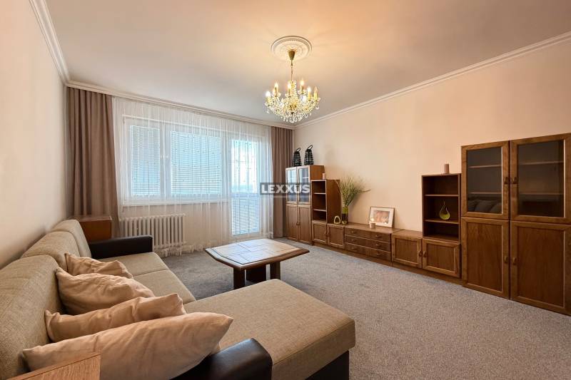 Living room with a sofa, wooden furniture set, and chandelier in a 3-room apartment.