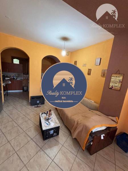 Living room in a family house with a bed, a small table, and arched doors.