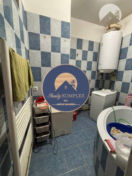 A bathroom with blue tiles and a washing machine in a family house, storage baskets for laundry.