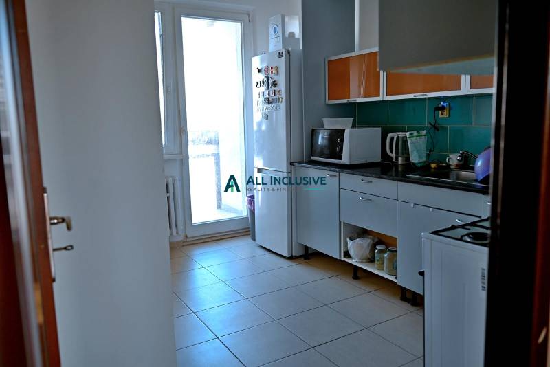 A kitchen with appliances and cabinets in a 3-room apartment with a balcony.